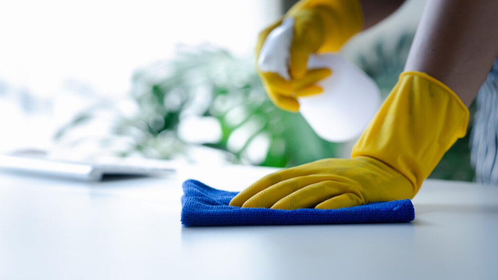 Person cleaning the room, cleaning staff is using cloth and spra